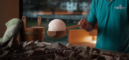 Saunameister legt eine Eiskugel auf den Saunaofen